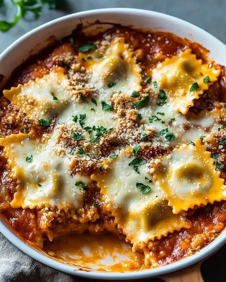 Cheesy baked ravioli casserole topped with melted cheese and herbs