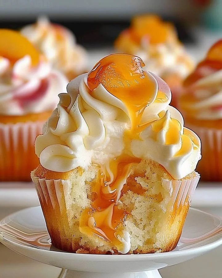 Delicious peach cupcakes topped with creamy peach frosting and fresh fruit.