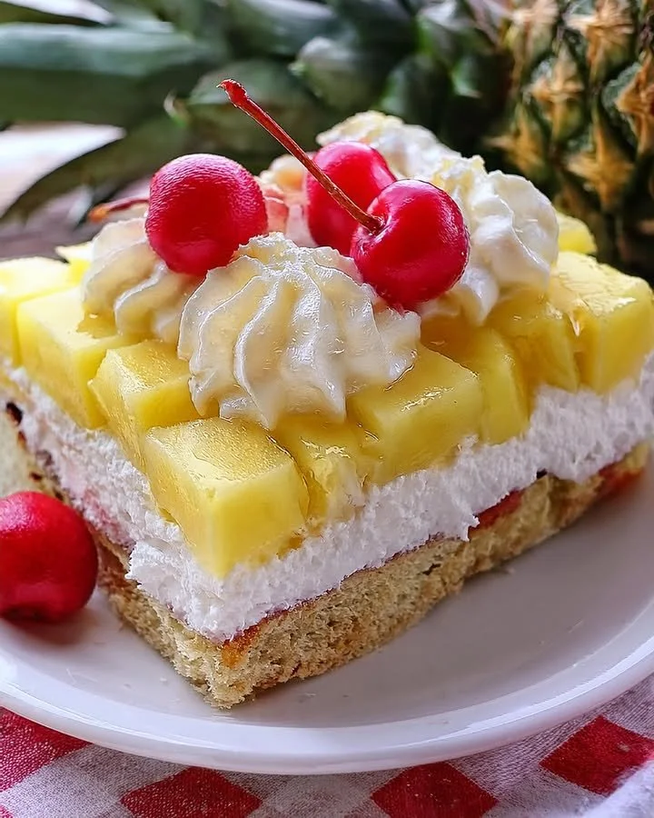 A delicious slice of Pineapple Heaven Cake topped with whipped cream and fresh pineapple