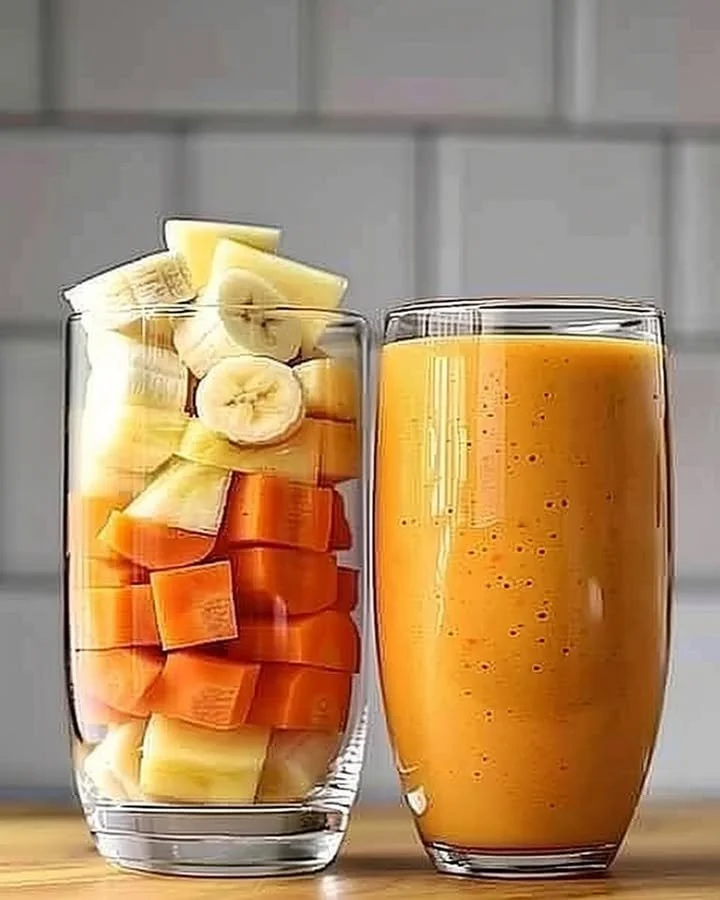 Pineapple Orange Carrot Smoothie in a glass with tropical fruits around