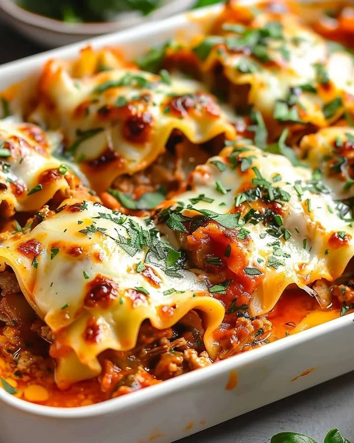 Delicious short rib lasagna rolls topped with melted cheese and fresh herbs