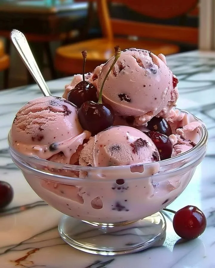 Bowl of creamy Cherry Swirl Ice Cream with a cherry drizzle on top.