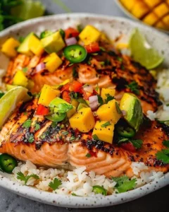 Grilled salmon fillet served with vibrant mango salsa on a plate.